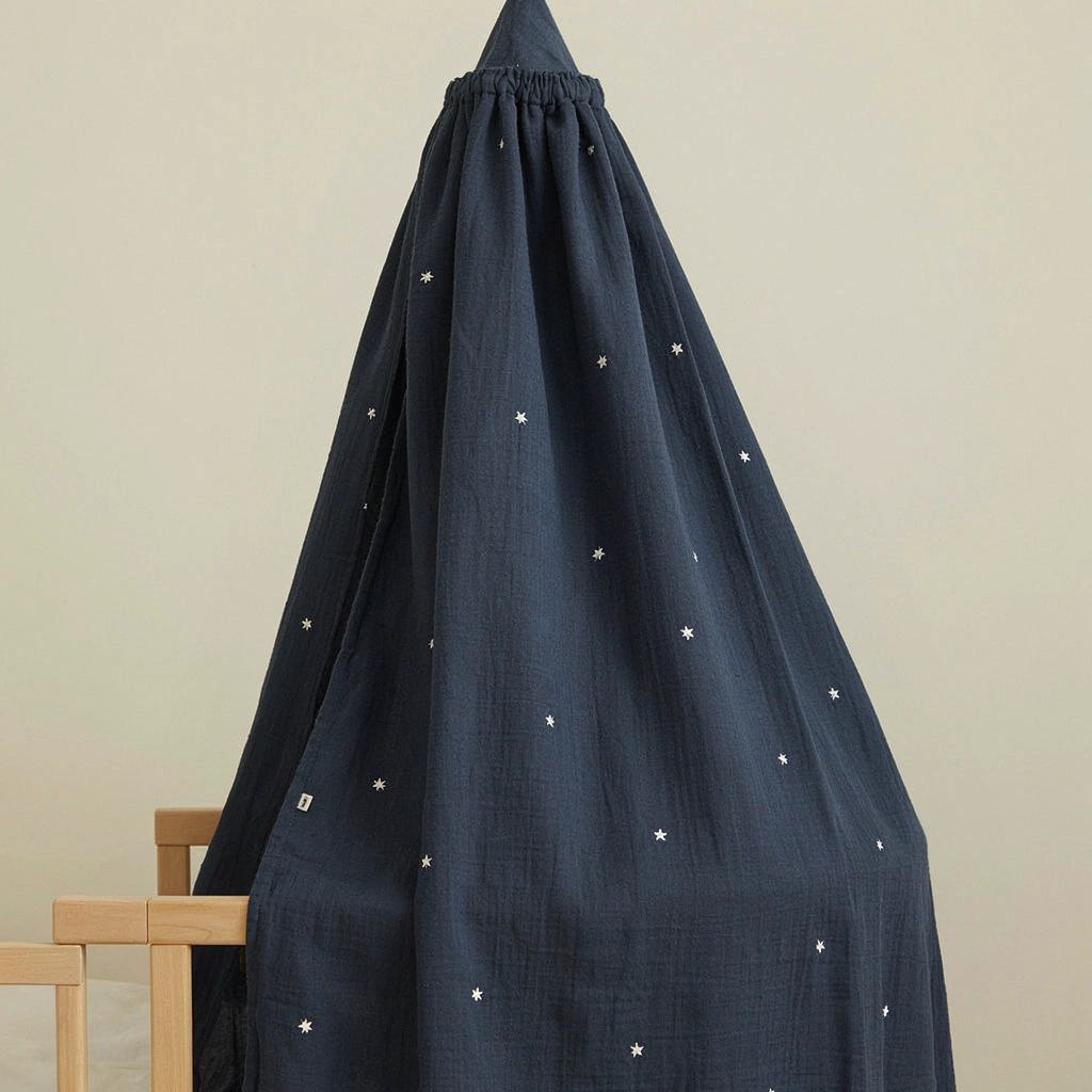 Voile de lit bébé bleu nuit parsemé d'étoiles au-dessus d'un lit à barreaux